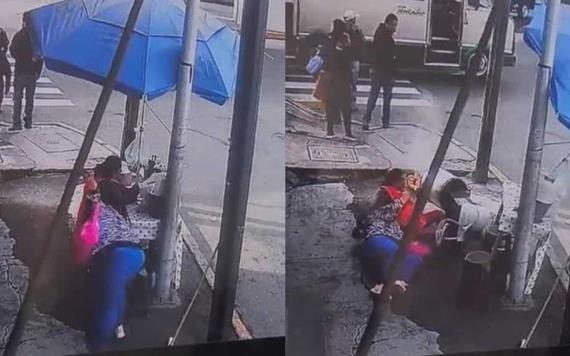 ¡Terrible caída! Mujer se tropieza y en su trayecto derriba un puesto de tamales