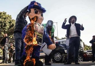 Activistas en apoyo a migrantes queman piñata de policía en protesta por abusos en Tijuana