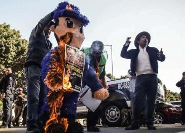 Activistas en apoyo a migrantes queman piñata de policía en protesta por abusos en Tijuana